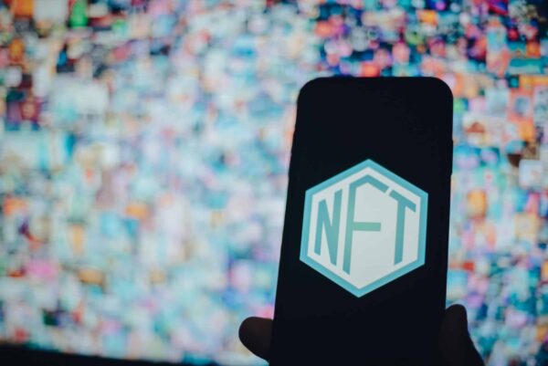 Une personne tenant un smartphone, le logo NFT sur l'écran